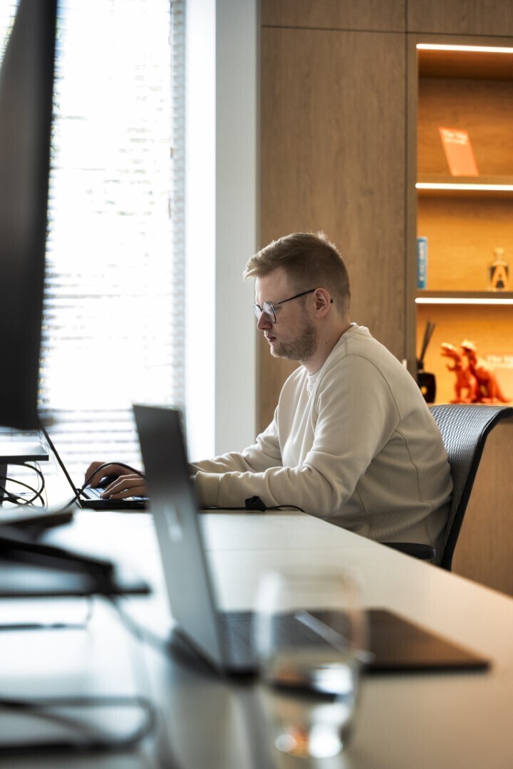 Een man die aan het typen is op een laptop aan een bureau