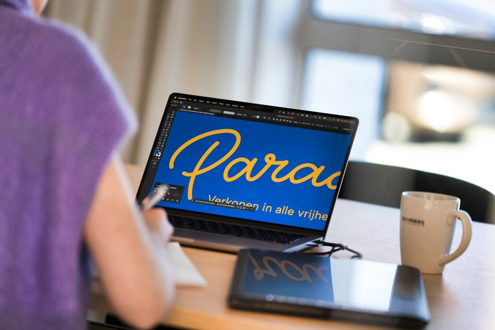 Persoon werkt op een laptop aan een grafisch ontwerp met het woord “Paraaf” en de slogan “Verkoop in alle vrijheid”.