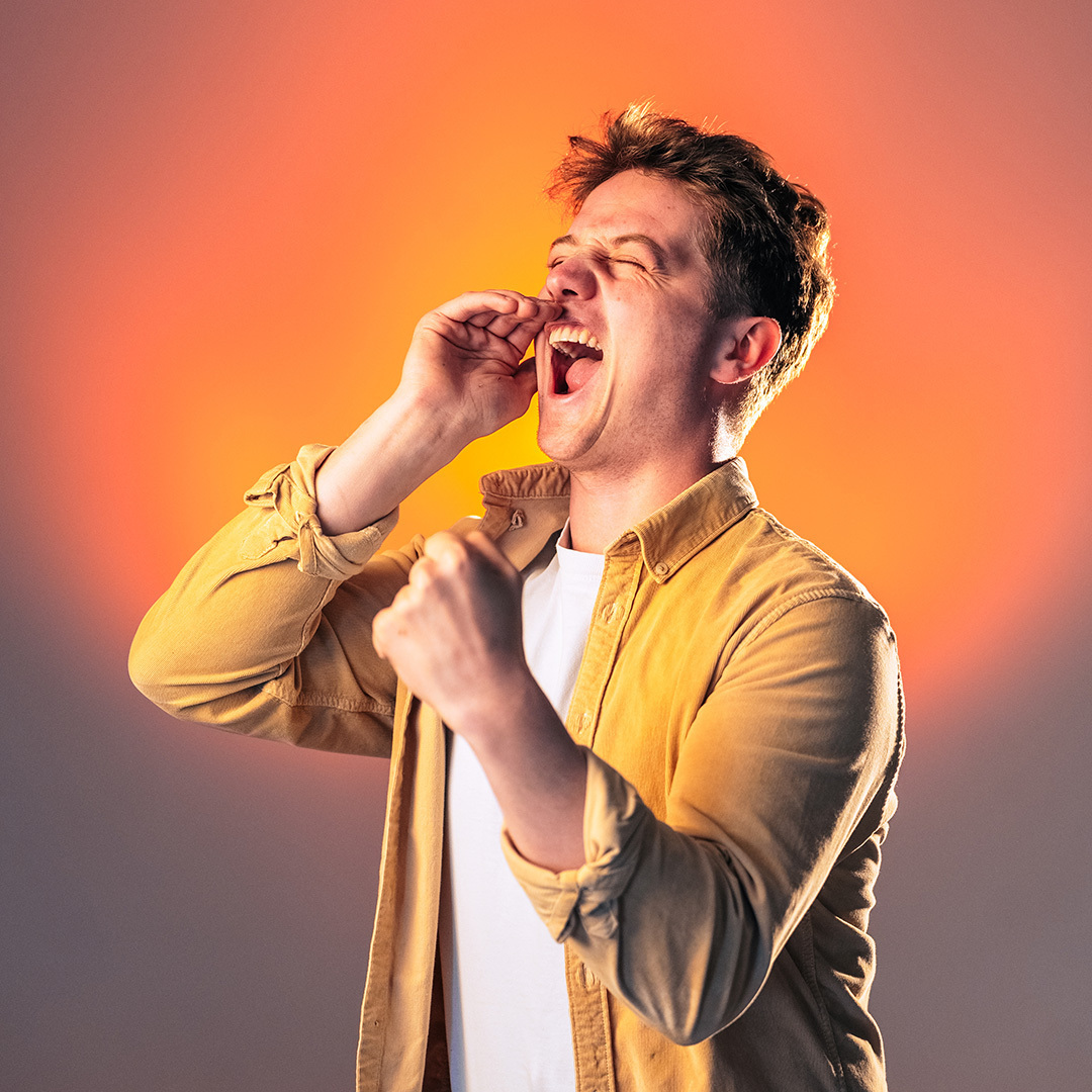 Zwart wit foto van man in een overhemd en wit T-shirt juicht enthousiast met een vuist in de lucht en hand bij zijn mond